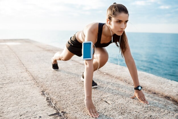 Joven hermosa chica deportiva preparándose para correr sobre la playa.