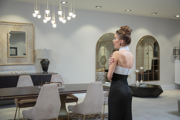 Joven hermosa dama con vestido y de pie en medio de la habitación