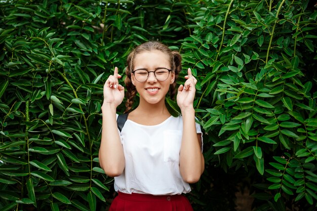 Joven hermosa estudiante en gafas con la esperanza, posando sobre las hojas al aire libre.