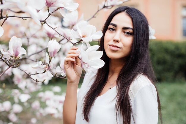 Joven hermosa joven cerca del árbol floreciente de la primavera