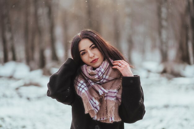 Joven hermosa modelo posando en bosque de invierno