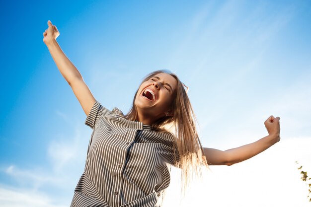 Joven hermosa mujer alegre caminando por la ciudad, sonriendo, regocijándose.