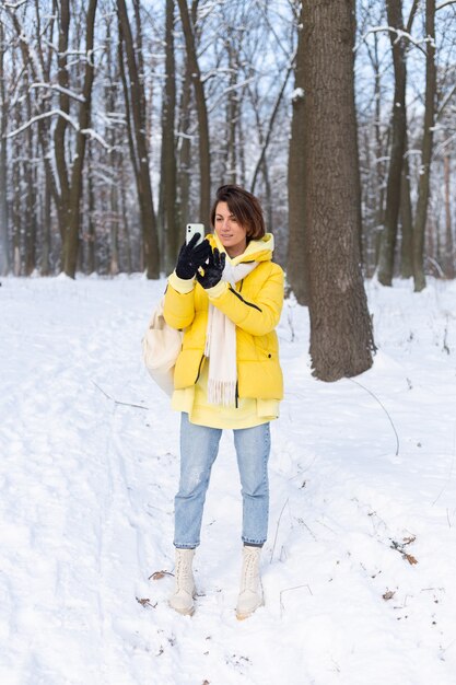 Joven hermosa mujer alegre feliz en el video blog del bosque de invierno, hace una foto selfie