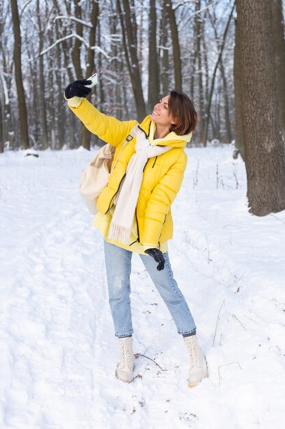 Joven hermosa mujer alegre feliz en el video blog del bosque de invierno, hace una foto selfie