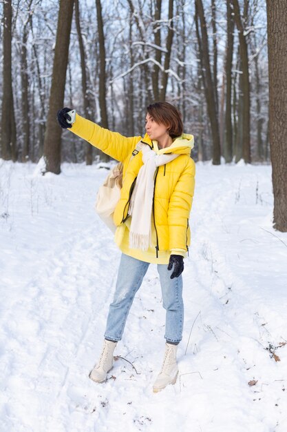 Joven hermosa mujer alegre feliz en el video blog del bosque de invierno, hace una foto selfie