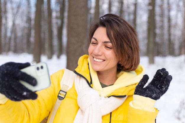 Joven hermosa mujer alegre feliz en el video blog del bosque de invierno, hace una foto selfie