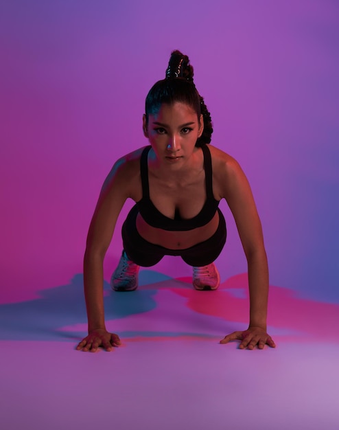 Joven hermosa mujer asiática con cuerpo atlético haciendo flexiones en el moderno gimnasio