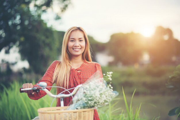 Joven hermosa mujer asiática montando una bicicleta en un parque