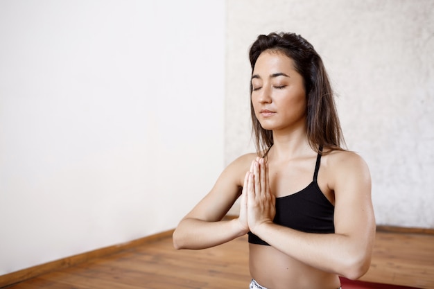 Joven hermosa mujer atlética practicando yoga interior en alfombra roja