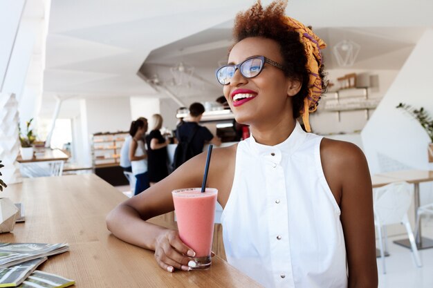 Joven hermosa mujer bebiendo batido sonriendo descansando en café