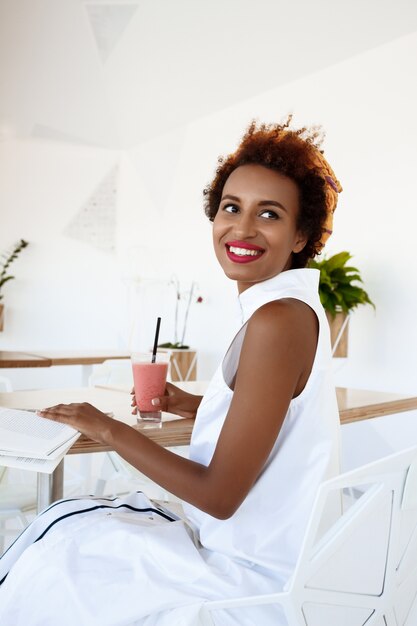 Joven hermosa mujer bebiendo batido sonriendo descansando en café