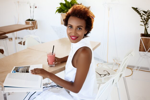 Joven hermosa mujer bebiendo batido sonriendo descansando en café