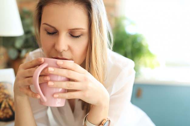 Joven hermosa mujer bebiendo café o té