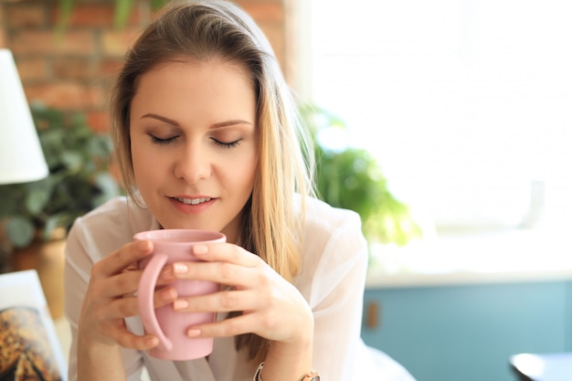 Joven hermosa mujer bebiendo café o té