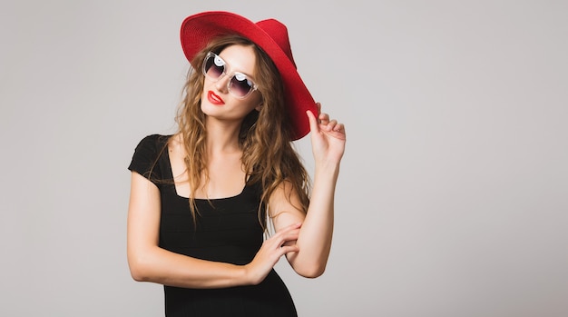 Joven hermosa mujer elegante en vestido negro y sombrero rojo