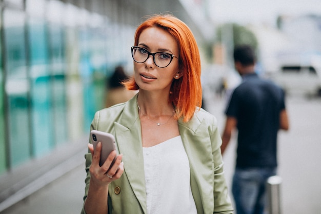 Joven hermosa mujer exitosa en traje verde hablando por teléfono