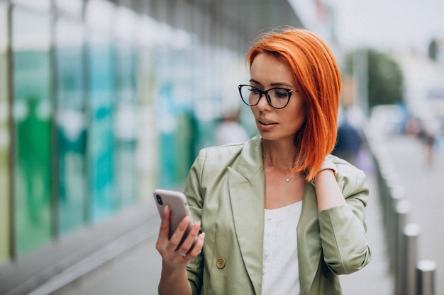 Joven hermosa mujer exitosa en traje verde hablando por teléfono