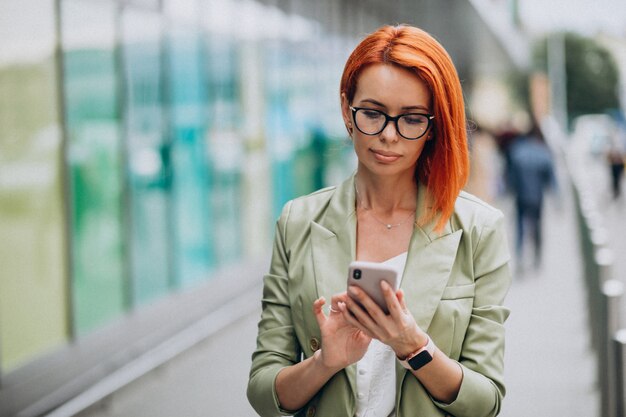 Joven hermosa mujer exitosa en traje verde hablando por teléfono