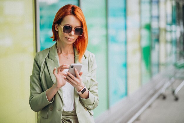 Joven hermosa mujer exitosa en traje verde hablando por teléfono