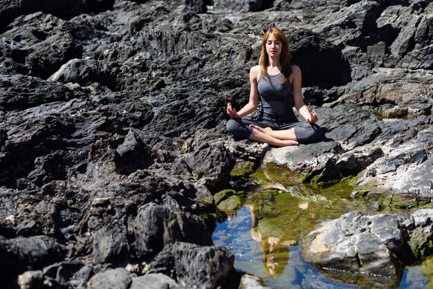 Joven hermosa mujer haciendo yoga en la naturaleza