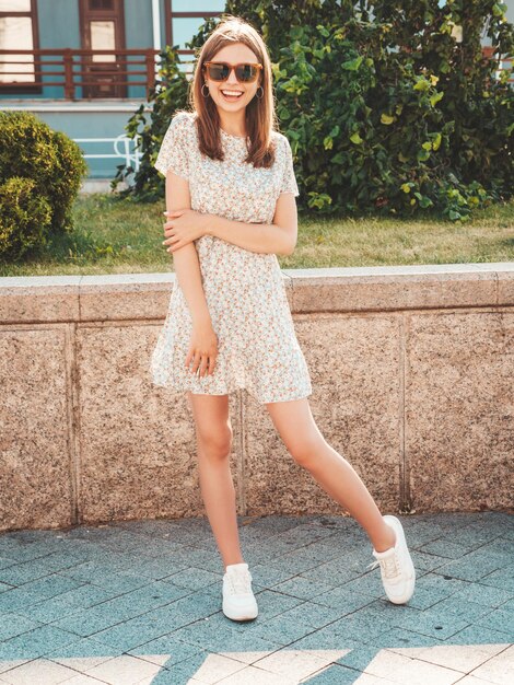 Joven hermosa mujer hipster sonriente en ropa de verano de moda Mujer sexy despreocupada posando en el fondo de la calle al atardecer Modelo positivo al aire libre Alegre y feliz en gafas de sol