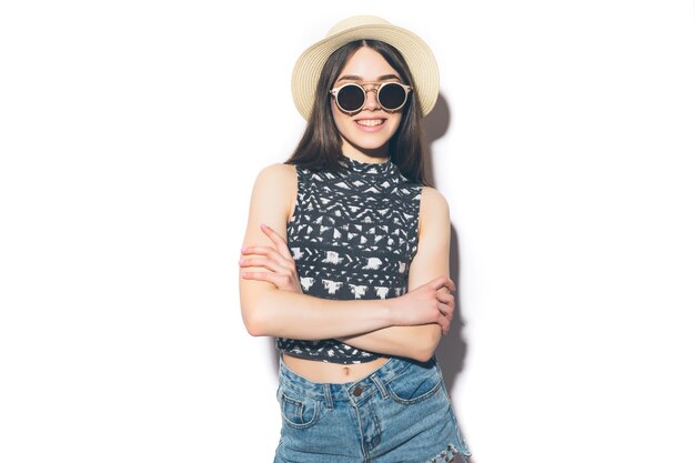 Joven hermosa mujer de moda con maquillaje de moda en sombrero negro y gafas en la pared gris. Modelo mirando, usando anteojos con estilo. Moda femenina, concepto de belleza.