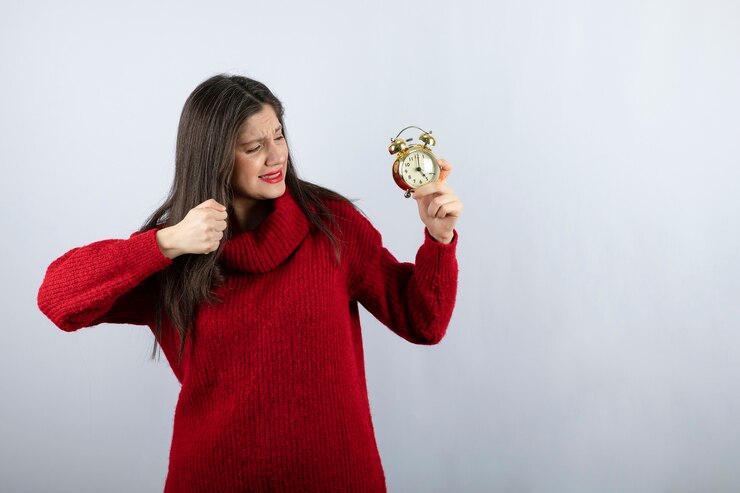 Foto gratuito joven hermosa mujer morena sosteniendo un reloj de alarma de pie sobre fondo blanco.