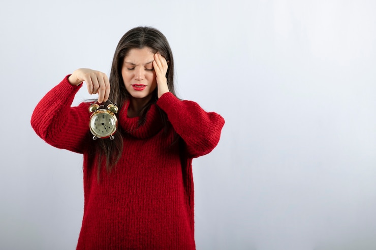 Foto gratuito joven hermosa mujer morena sosteniendo un reloj de alarma de pie sobre fondo blanco.