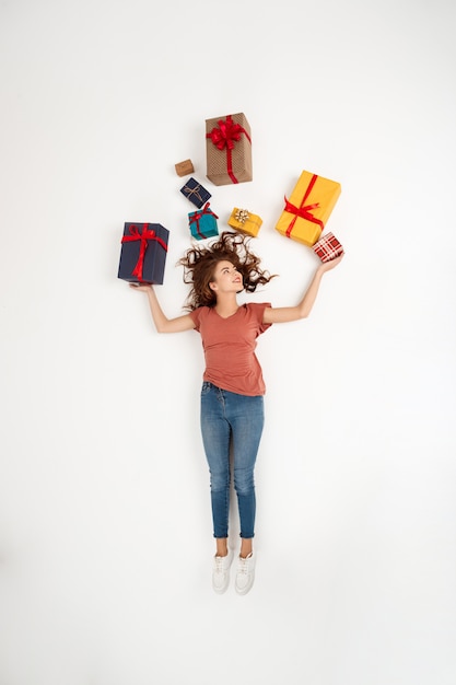 Joven hermosa mujer rizada acostada entre cajas de regalo