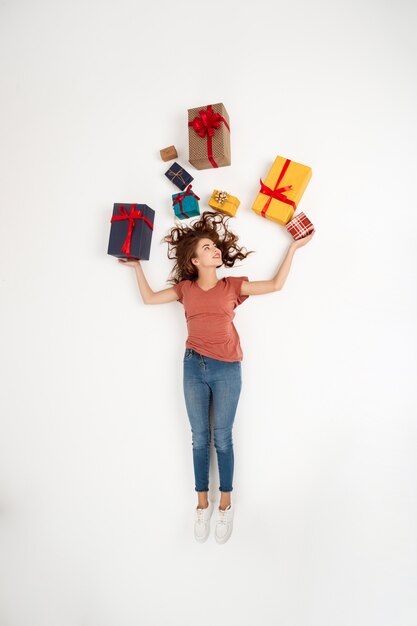 Joven hermosa mujer rizada acostada entre cajas de regalo