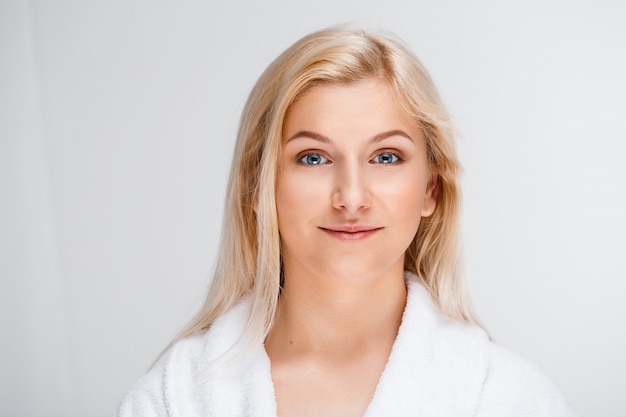 Joven hermosa mujer rubia en bata de baño sonriendo