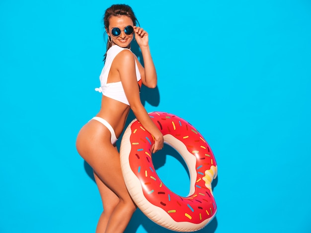 Joven hermosa mujer sexy sonriente en gafas de sol. Chica en calzoncillos blancos de verano y tema con colchón inflable donut lilo.