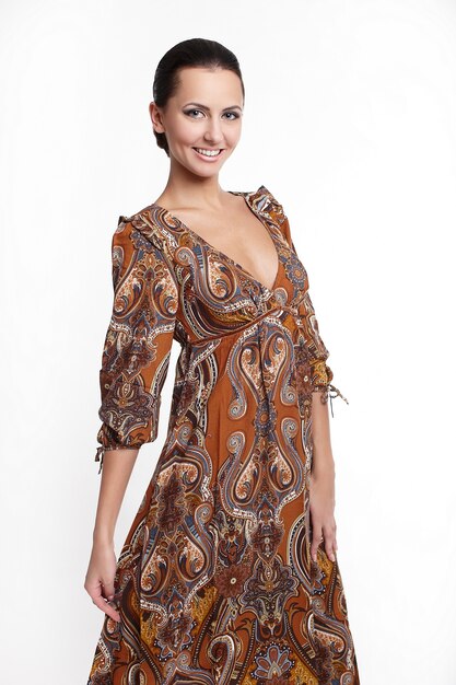 Joven hermosa mujer sonriente en colorido vestido de verano marrón aislado en blanco