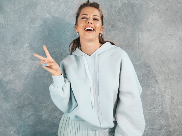 Joven hermosa mujer sonriente mirando. Chica de moda en ropa casual de verano con capucha y falda.