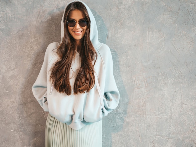 Joven hermosa mujer sonriente mirando. Chica de moda en ropa casual de verano con capucha y falda.