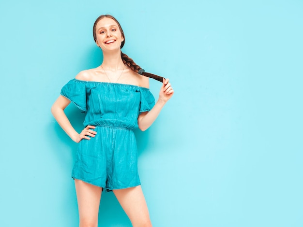 Joven hermosa mujer sonriente en overoles de jeans de verano de moda Mujer sexy despreocupada con peinado de cola posando junto a la pared en el estudio Modelo positivo divirtiéndose Alegre y feliz Aislado