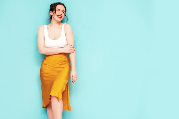 Joven hermosa mujer sonriente en ropa de falda amarilla de verano de moda Mujer sexy despreocupada posando junto a la pared en el estudio Modelo positivo divirtiéndose Alegre y feliz Aislado