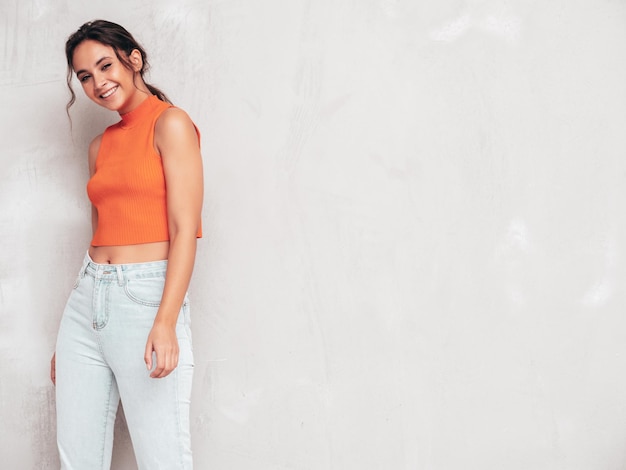 Joven hermosa mujer sonriente en ropa de verano de moda Mujer sexy despreocupada posando junto a la pared gris en el estudio Modelo morena positiva divirtiéndose y volviéndose loca Alegre y feliz