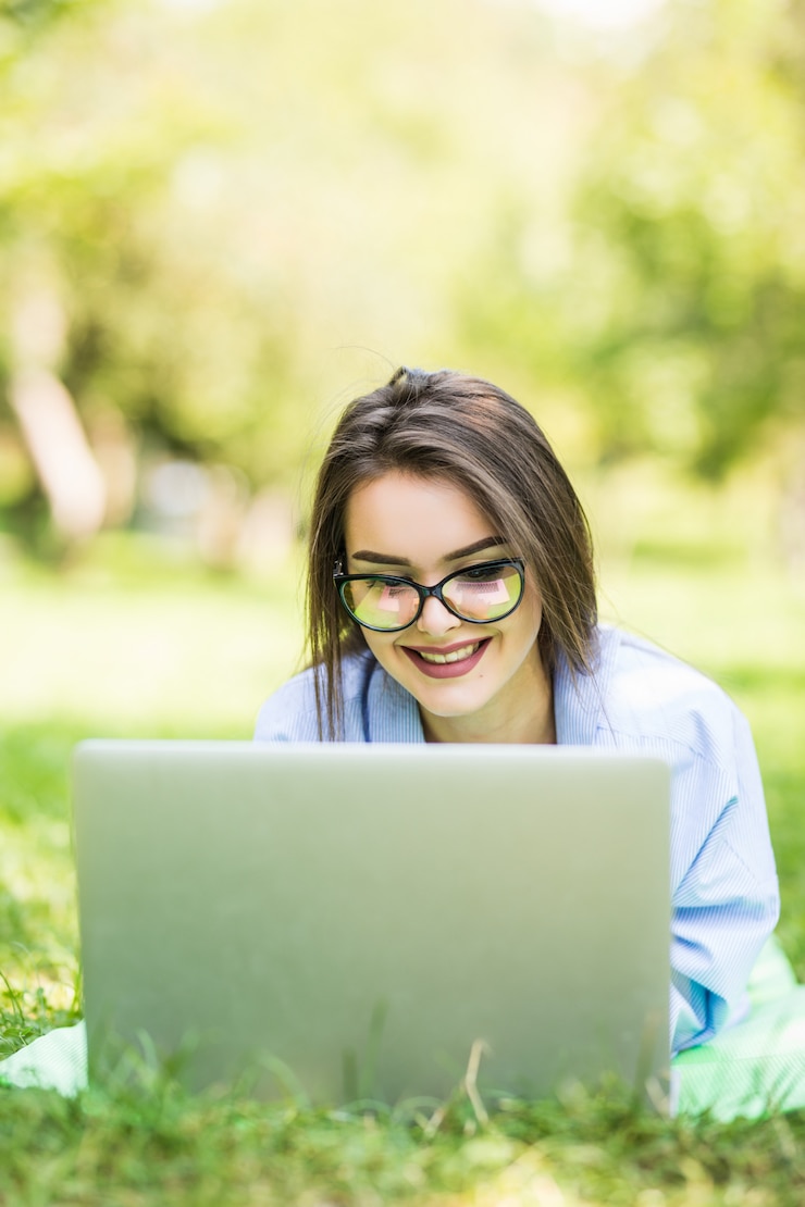 Foto gratuito joven hermosa mujer sonriente usando laptop en citypark en día soleado