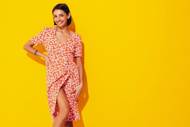 Joven hermosa mujer sonriente en vestido rojo de verano de moda Sexy mujer despreocupada posando junto a la pared amarilla en el estudio Modelo positivo divirtiéndose Alegre y feliz Aislado