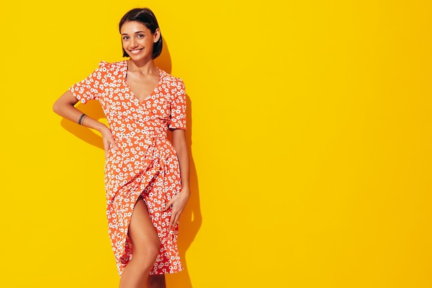 Joven hermosa mujer sonriente en vestido rojo de verano de moda Sexy mujer despreocupada posando junto a la pared amarilla en el estudio Modelo positivo divirtiéndose Alegre y feliz Aislado