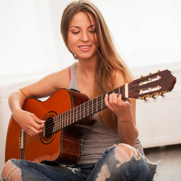 Joven hermosa mujer tocando la guitarra