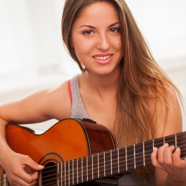 Joven hermosa mujer tocando la guitarra