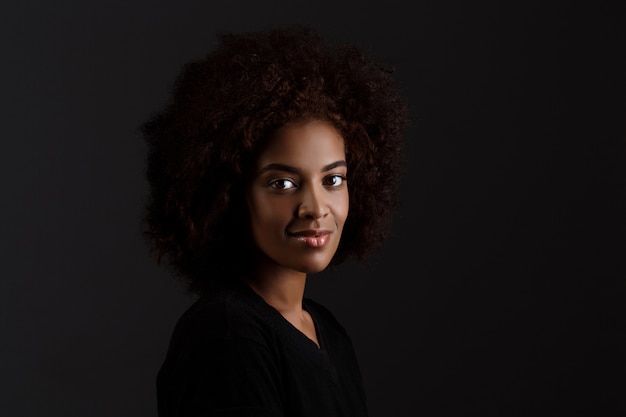 Foto gratuita joven hermosa niña africana sonriendo sobre pared oscura