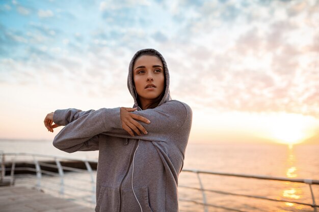 Joven hermosa niña deportiva entrenamiento al amanecer sobre el mar.