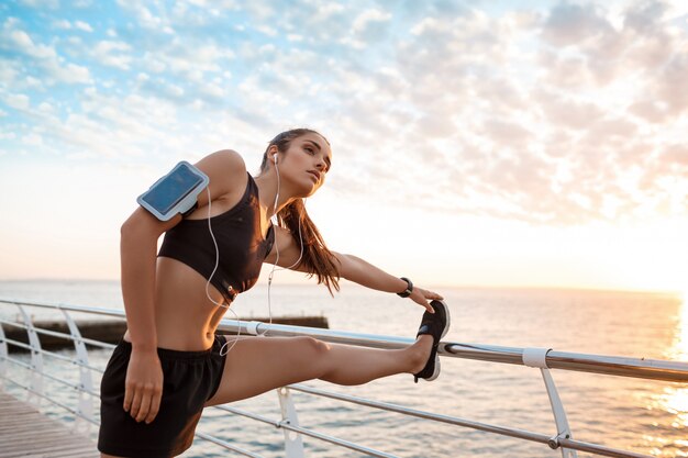 Joven hermosa niña deportiva entrenamiento al amanecer sobre el mar.