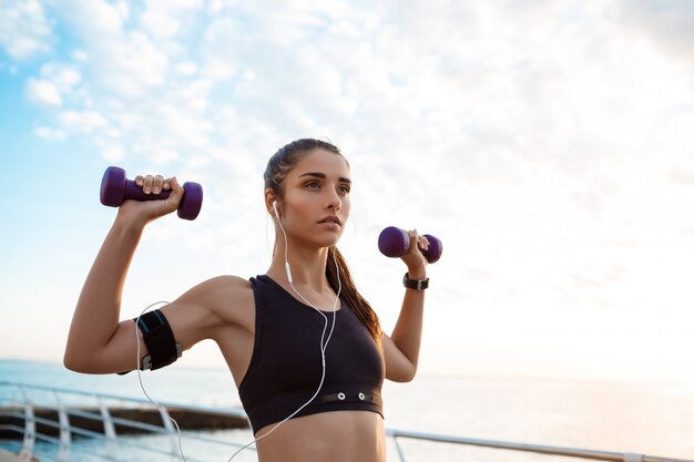 Joven hermosa niña deportiva entrenamiento al amanecer sobre el mar.