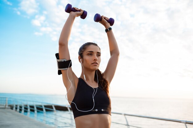 Joven hermosa niña deportiva entrenamiento al amanecer sobre el mar.