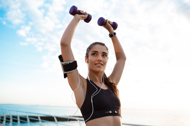 Joven hermosa niña deportiva entrenamiento al amanecer sobre el mar.