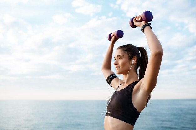 Joven hermosa niña deportiva entrenamiento al amanecer sobre el mar.